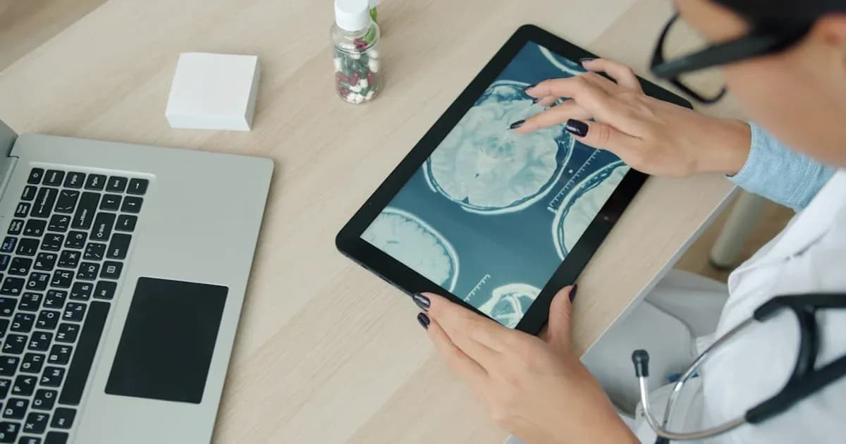 Doctor examining brain scan on tablet at desk.