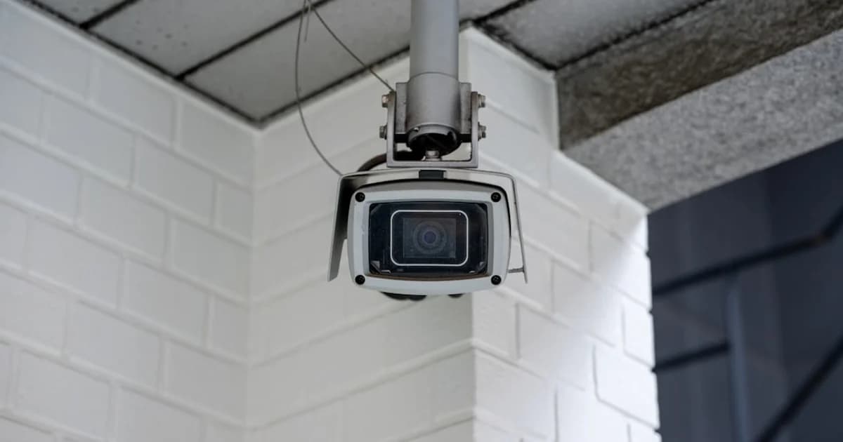 Security camera mounted on a white brick wall.